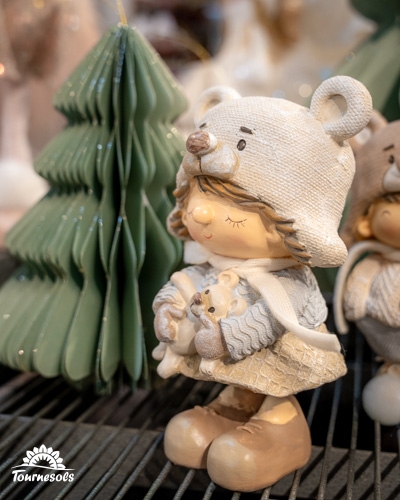 Figurine d'enfant en tenue d'hiver devant un sapin, marché de Noël 2025.